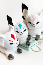 Load image into Gallery viewer, White fox stuffed animals with red, blue, and pink markings.
